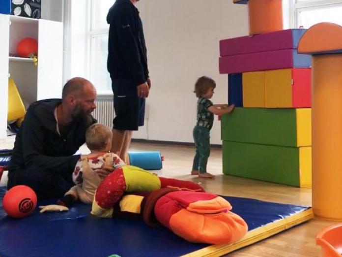 En Far og børn der sidder med alle legesagerne