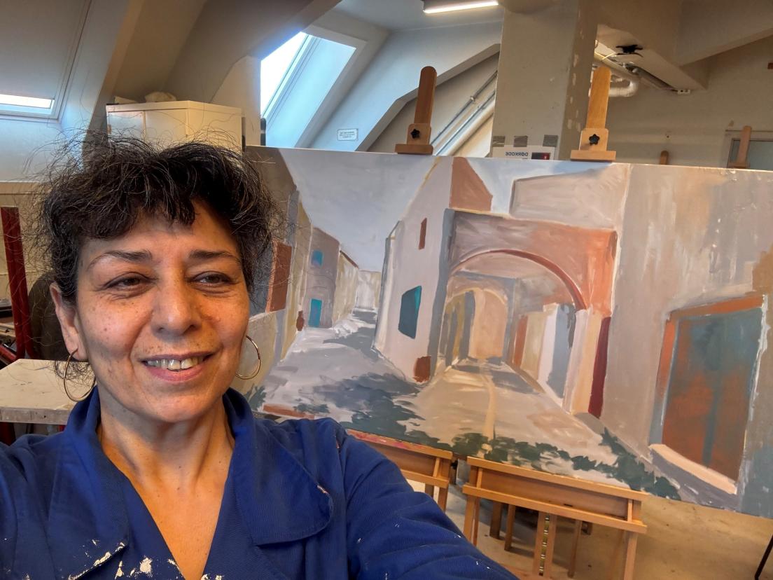 Foto af kunstner med maleri i baggrunden